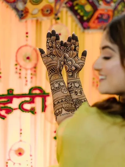 A lovely shot of a client showing off her mehendi against a festive 'Haldi' backdrop. The design is intricate and perfect for the wedding celebrations.