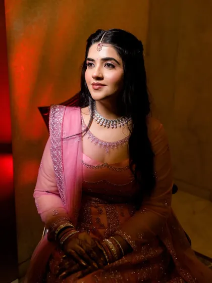 A lovely portrait of the bride in her pink lehenga, captured with warm, dramatic lighting. Her gentle smile and elegant posture make this a timeless image.