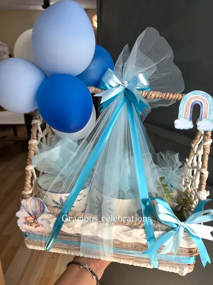 A premium return favor option for a baby boy's birthday. This hamper includes two mugs, a jade planter, and three jars of eatables, all decorated with a cute hot air balloon and rainbow theme.