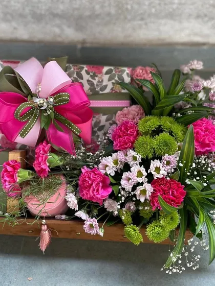 This vibrant hamper is bursting with color and joy. We paired floral-patterned gift boxes with a stunning bouquet of pink and green carnations, all nestled in a rustic wooden tray for a gift that is both cheerful and chic.