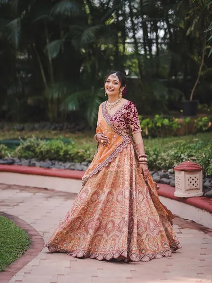 A full-length shot showing how the elegant updo balances her ornate lehenga. The look is designed to photograph like a dream.