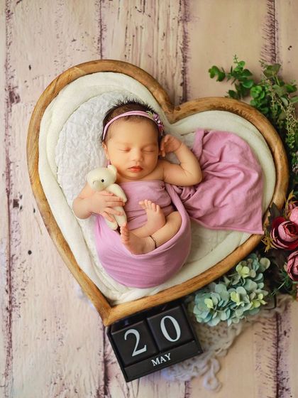 A full-length view of a baby girl in our heart-shaped prop, decorated with flowers and a date block. This type of shot is perfect for announcements or the first page of a baby album.