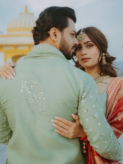 A close, romantic portrait where the bride embraces the groom from behind, showcasing their connection and her Mehendi.