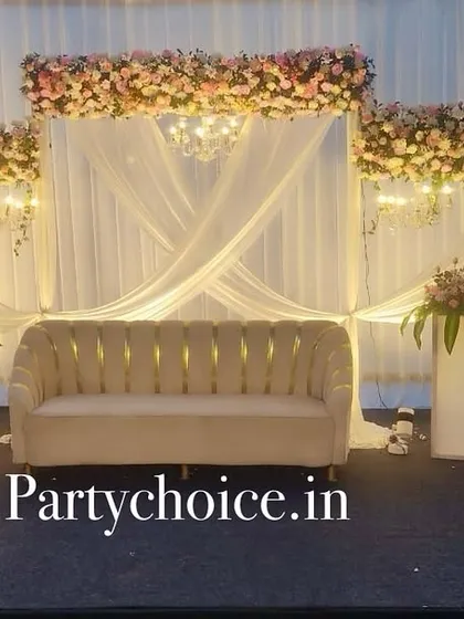An elegant outdoor engagement stage at dusk. The white drapes, floral headers, and chandeliers create a magical and romantic atmosphere.