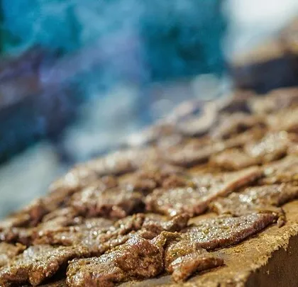 A close-up of meat sizzling on a hot stone slab, a unique cooking method that locks in flavor and provides great entertainment for guests.