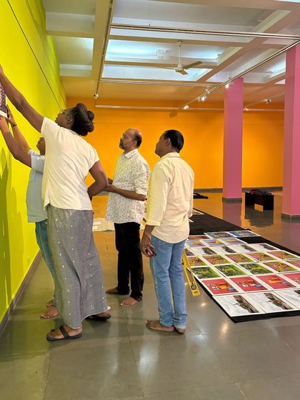 A behind-the-scenes shot of the installation process for 'No Longer A Memory', with the team carefully hanging the works.