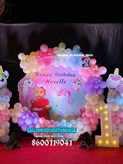 Narelle's first birthday with a pastel unicorn theme. This setup includes a round photo backdrop, a soft-colored balloon garland, and cute unicorn cutouts on balloon pillars.