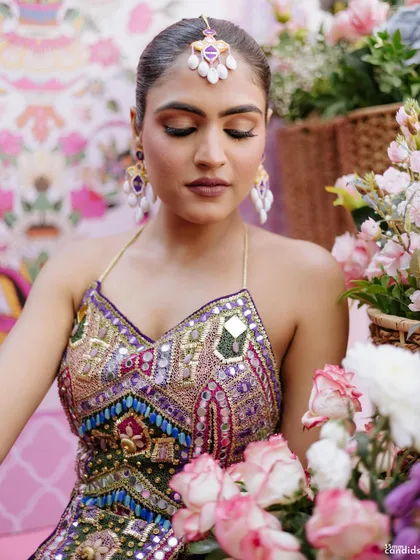 A close-up of the bride's sleek Mehendi look, with a simple, tight braid that allows her colorful outfit and jewelry to take center stage.