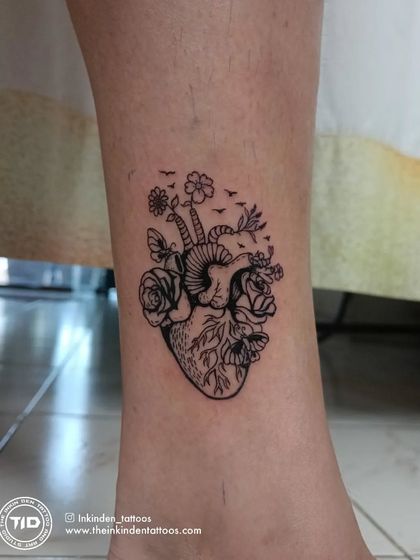 An anatomical heart blooming with flowers and butterflies. This intricate line-work tattoo symbolizes a heart full of life, growth, and the beauty of nature.