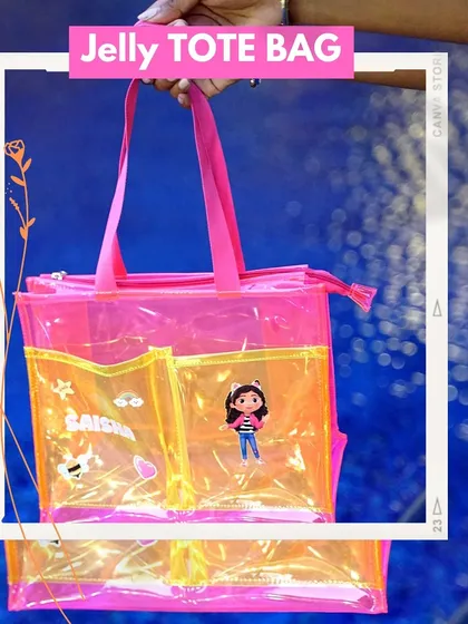 Our jelly tote bag in a vibrant pink and yellow design. This spacious bag is customized with the name 'Saisha' and character patches, perfect for carrying everyday essentials in style.