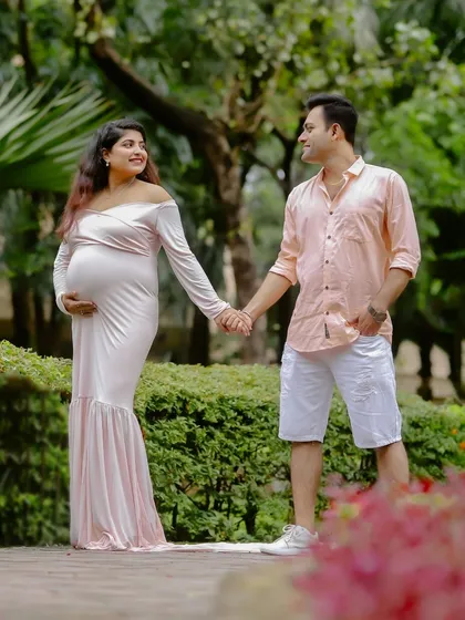 A candid shot of the couple holding hands and sharing a look of love and anticipation during their park maternity session.