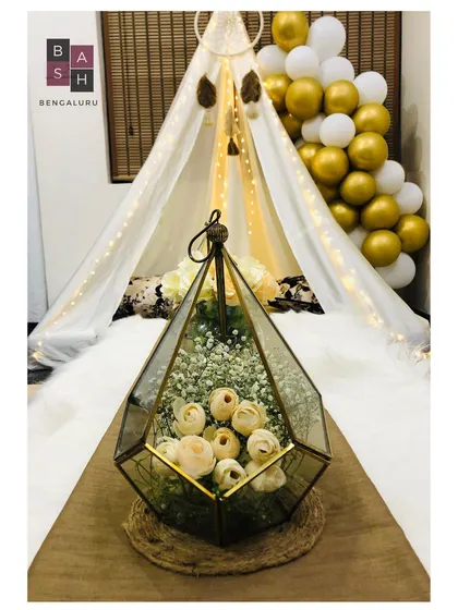 A close-up of the details from our chic boho tent setup. This geometric brass and glass terrarium holds delicate white flowers and baby's breath, adding a touch of modern elegance to the tablescape.