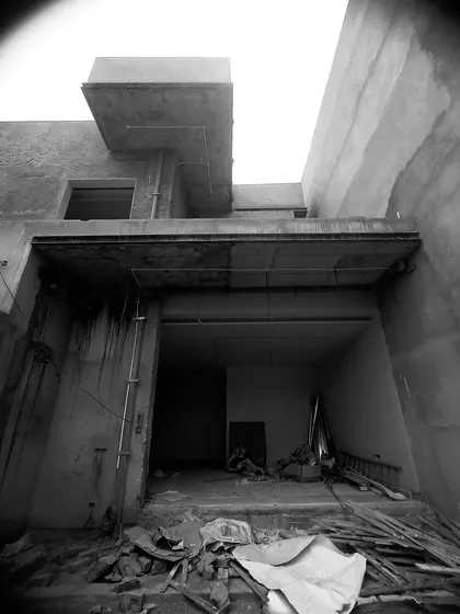 Debris and raw materials on the ground floor of a site, looking up at the concrete overhangs and structure above.