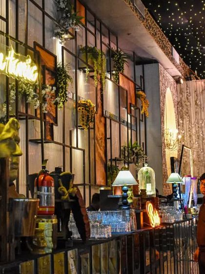 For this event, I created an elaborate wall-mounted bar setup. It features integrated shelving, floral arrangements, and a 'Gin n tonic' neon sign, turning an entire wall into a sophisticated beverage experience.