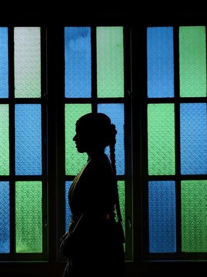 A striking silhouette of a bride against a colorful stained-glass window. This artistic shot is all about shape, color, and mood.