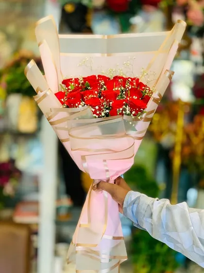 Another view of the red rose bouquet, held to show its size and the elegant effect of the striped wrapping paper.