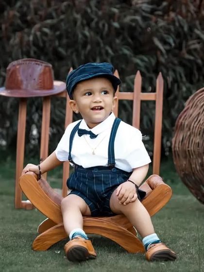 A charming outdoor session with a vintage musician theme. The little boy is dressed smartly with a bow tie and suspenders, surrounded by props like a ukulele and an old telephone.