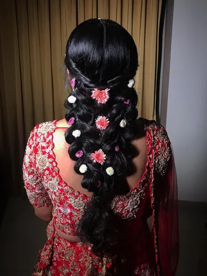 A stunning triple braid hairstyle for a bride, woven with fresh flowers for a unique and textured wedding day look.