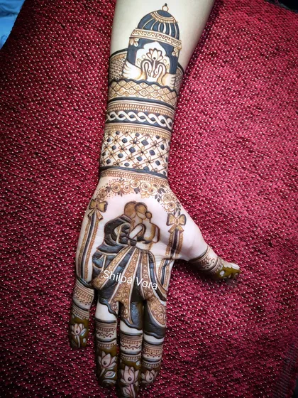 An engagement mehndi design featuring a romantic couple silhouette. The design extends up the arm with swan motifs and intricate bands.