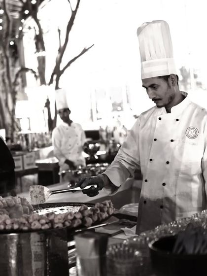 A black and white photo of a chef at a live station, capturing a timeless moment of culinary craftsmanship.
