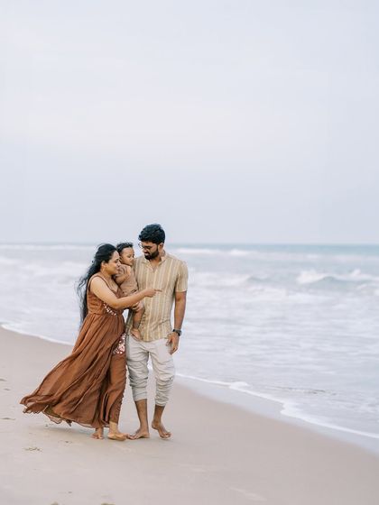 A family walking along the shoreline. The wind in their hair and the waves at their feet create a dynamic and beautiful scene.