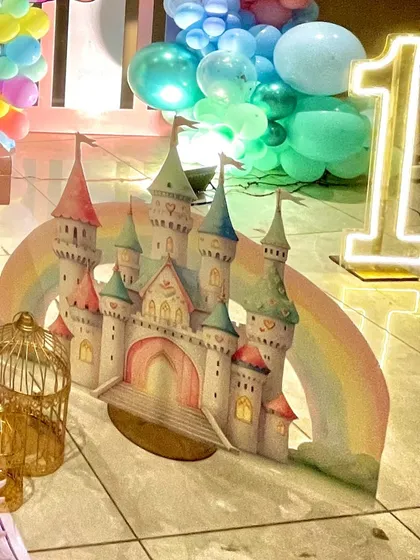 A beautiful cutout of a pastel-colored unicorn castle, complete with a rainbow arch and a large light-up number '1' for the first birthday celebration.