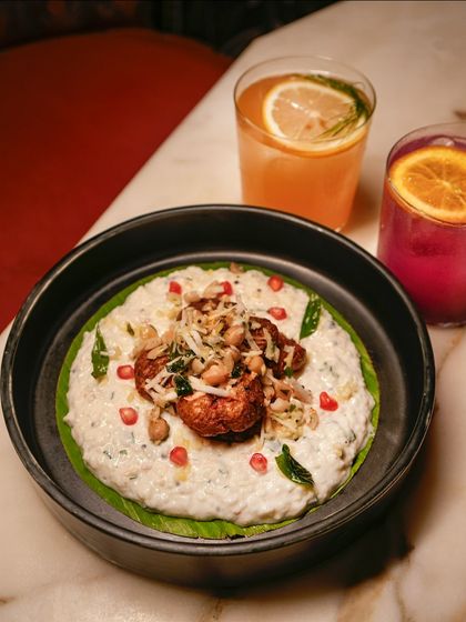 Comfort in every bite. Our take on curd rice, topped with crispy chicken and pomegranate seeds, sits alongside two of our vibrant house cocktails.