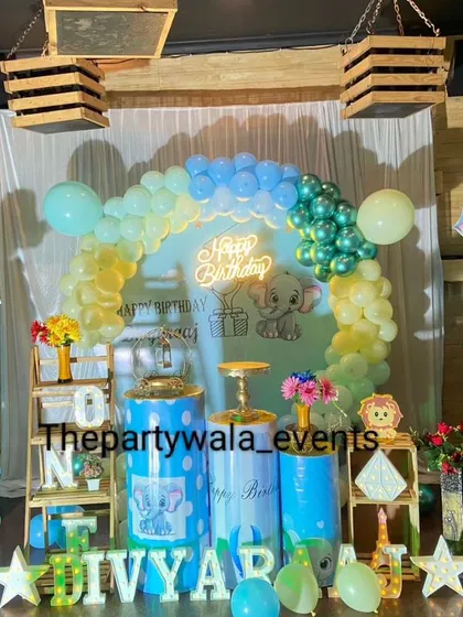 A baby elephant theme with a softer color palette of pastel blue and yellow. The wooden crates and hanging baskets add a rustic touch.