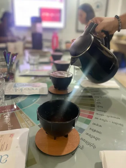 Pouring hot water over freshly ground coffee for a cupping session. This step, called "breaking the crust," releases the coffee's aroma.