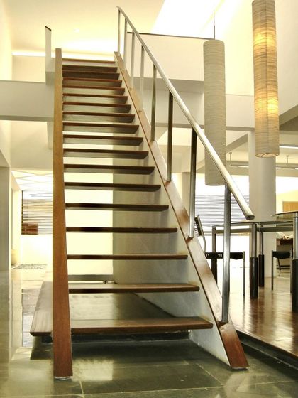 A simple, elegant wooden staircase in the Zanav Home Studio. The open-riser design allows light and views to pass through, contributing to the overall sense of lightness and transparency in the space.