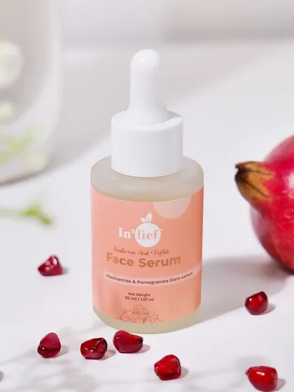 A bright, naturally styled shot of the In'lief face serum next to a whole pomegranate. This composition clearly communicates the product's main ingredient and its fresh, natural appeal.