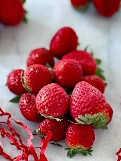 A pile of fresh, vibrant strawberries. We use only the best and freshest ingredients in our cakes, tarts, and pastries to ensure the highest quality.