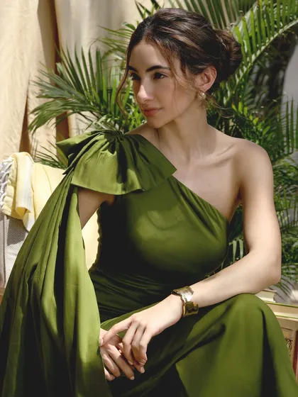 A dreamy, sun-kissed look for a fashion campaign. The makeup is warm and bronzed, with a dewy finish that catches the light beautifully, perfectly matching the outdoor setting and the olive green gown.