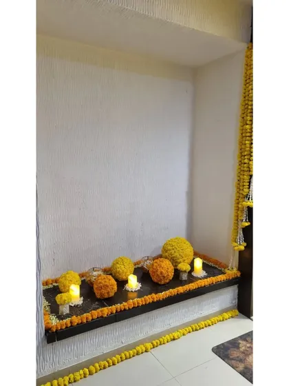 A simple shelf decorated with marigold balls and candles. This shows how we can use minimal elements to bring a festive and coordinated look to any part of your home for an intimate celebration.