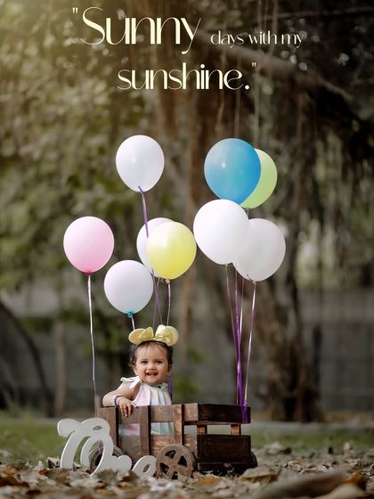 Sunny days with my sunshine. A joyful outdoor portrait featuring a wooden train cart and colorful balloons to celebrate a birthday.