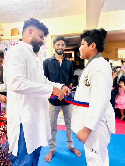 A student smiles as he receives his red and blue belt.