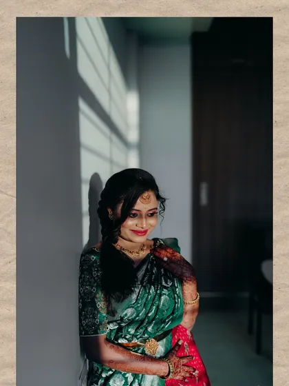 A portrait of a bride in a green and red half-saree, captured with beautiful natural light and shadows.