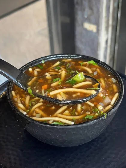 A spoonful of my hearty Manchow soup, filled with finely chopped vegetables and noodles.