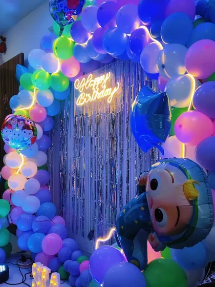 A colorful Cocomelon birthday setup in a home, featuring a circular balloon arch and foil character balloons.