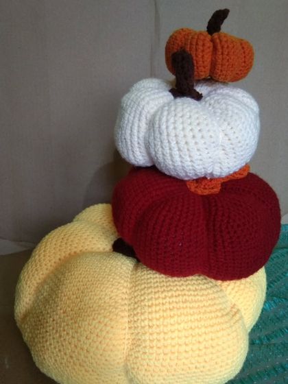 A stack of my handmade crochet pumpkins in various fall colors. These amigurumi props are perfect for autumn-themed photoshoots, adding a cozy, harvest feel.