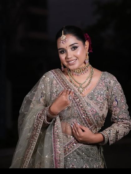 A happy client posing in a grey and pink embroidered lehenga. This is one of our most popular plus-size friendly options.