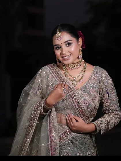 A smiling portrait of the client, highlighting the matching pink and gold jewellery set rented with the lehenga.