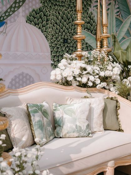 Custom-printed cushions with a palm leaf motif, perfectly complementing the hand-painted backdrop and adding a layer of comfort and style to the lounge seating.