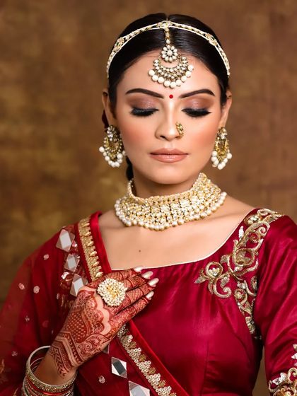 Setting new trends for our brides. This look features nude glowy eyes and lips, a modern take on bridal makeup that pairs beautifully with a traditional red saree.