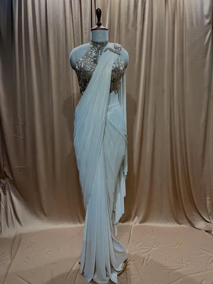 An elegant off-white drape saree featuring a stunning gold sequined halter-neck blouse. The perfect ensemble for a sophisticated evening event.