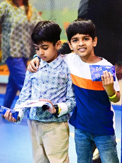 Two boys show off their Raksha Bandhan gifts and crafts, capturing a moment of sibling joy.