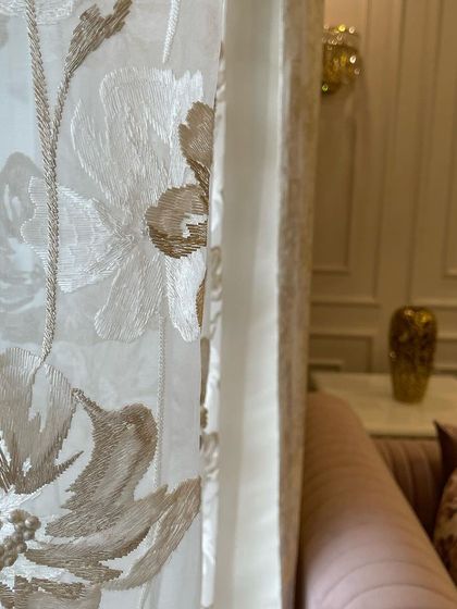A detail shot of the sheer curtains, which feature delicate floral embroidery. Layering sheers with heavier curtains adds privacy while still allowing soft, diffused light to enter the room.