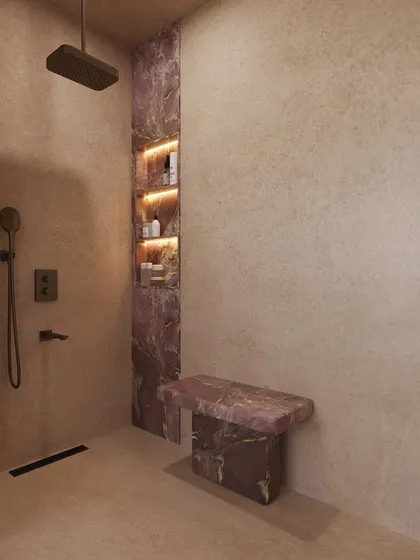 The walk-in shower features a built-in bench and niche, both made from the same beautiful pink stone, creating a cohesive and luxurious feel.