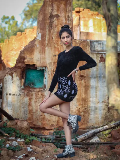 A dynamic pose that highlights the model's long legs and the interesting texture of the ruined wall behind her.