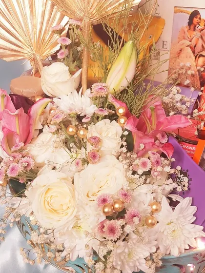 A luxurious floral gift hamper, perfect for an anniversary. This arrangement combines fresh flowers with gourmet chocolates and a personalized photo frame, creating a truly romantic and impressive gift.